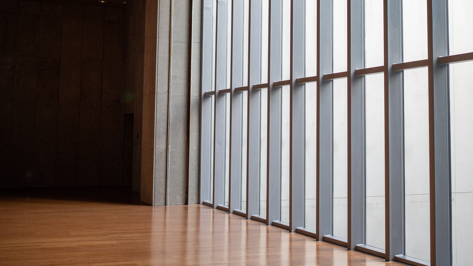 Modern architecture with wooden flooring and large vertical windows framed in metal, allowing natural light, used decoratively on a page discussing global capital markets and investment competition.